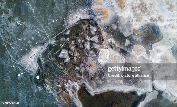 March 2018, Germany, Grossraeschen: The flat shore areas of the Grossraeschen lake are covered in ice . The brown coal open pit has been flooded for...