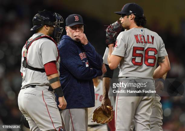 Pitching coach Dana LeVangie of the Boston Red Sox speaks to Sandy Leon and Joe Kelly on the mound during the eighth inning of the game against the...