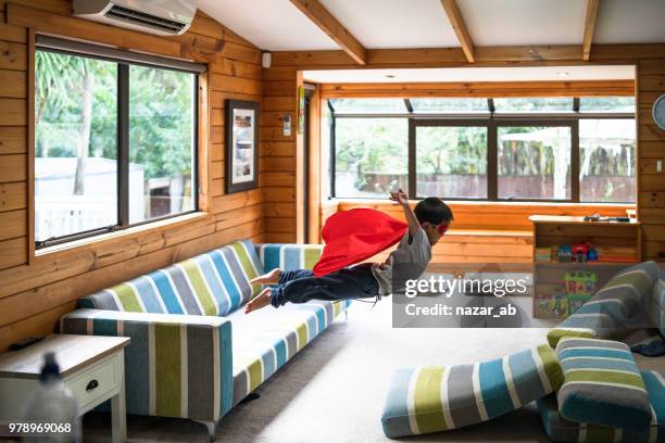 kid met superheld masker springen op de bank. - risico stockfoto's en -beelden