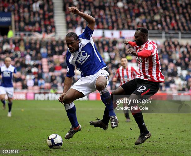 Cameron Jerome of Birmingham City gets tackled by John Mensah of Sunderland during the Barclays Premier League match between Sunderland and...