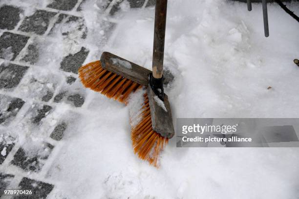 March 2018, Germany, Wyk: A snapped broom left standing in the snow on a pavement on the island of Foehr. The north sea island has not seen this much...