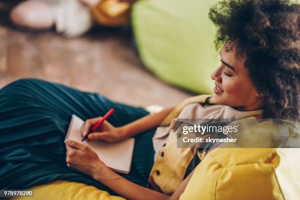 happy african american woman taking notes in a notebook. - creative writer stock pictures, royalty-free photos & images