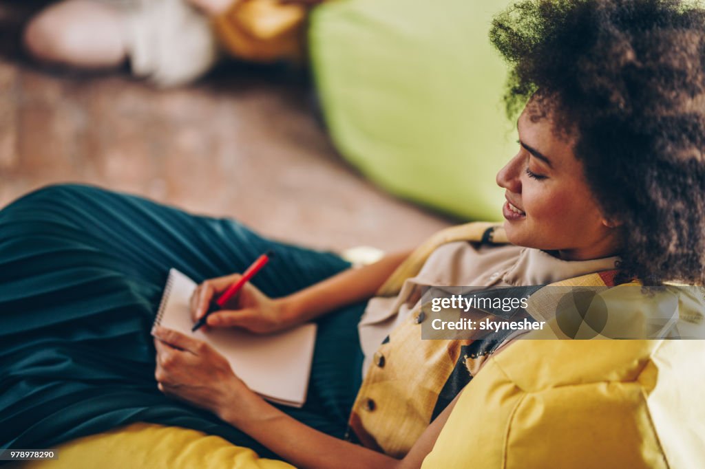 Feliz mulher afro-americana anotando em um caderno.