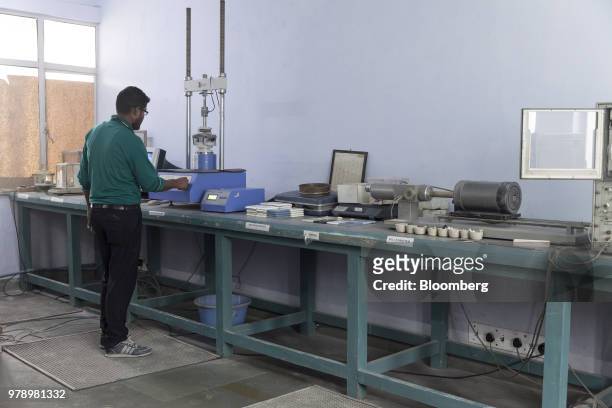 An employee tests the strength of ceramic samples with a digital modulus of rupture machine in the Research & Development Laboratory at the HSIL Ltd....