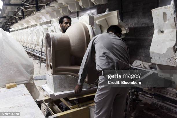 Employees remove a cast toilet bowl from a battery mold at the HSIL Ltd. Factory in Bahadurgarh, Haryana, India, on Monday, June 11, 2018. Indian...