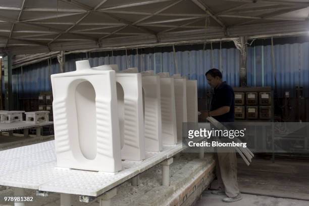An employee works a kiln-fired squat-toilet on a workbench at the HSIL Ltd. Factory in Bahadurgarh, Haryana, India, on Monday, June 11, 2018. Indian...