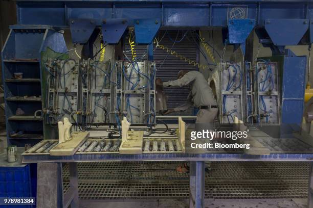 An employee removes a cast wash basin from a pressure mold machine at the HSIL Ltd. Factory in Bahadurgarh, Haryana, India, on Monday, June 11, 2018....
