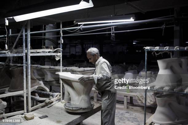 An employee repairs a cast toilet bowl at the HSIL Ltd. Factory in Bahadurgarh, Haryana, India, on Monday, June 11, 2018. Indian Prime Minister...