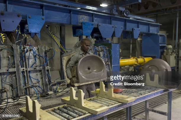 An employee carries a cast wash basin from a pressure mold machine to a workbench at the HSIL Ltd. Factory in Bahadurgarh, Haryana, India, on Monday,...