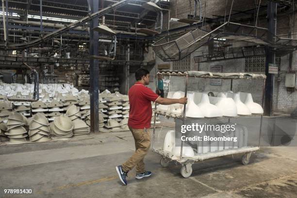 An employee uses a cart to transport fired toilet bowls and washbasins at the HSIL Ltd. Factory in Bahadurgarh, Haryana, India, on Monday, June 11,...