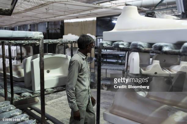 An employee checks glazed sanitaryware parts on racks at the HSIL Ltd. Factory in Bahadurgarh, Haryana, India, on Monday, June 11, 2018. Indian Prime...