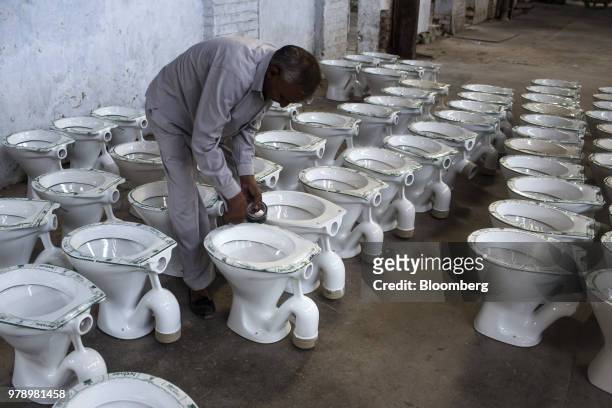 An employee applies Hindware branded tape to toilet bowls at the HSIL Ltd. Factory in Bahadurgarh, Haryana, India, on Monday, June 11, 2018. Indian...