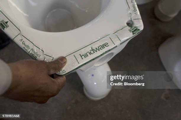 An employee applies Hindware branded tape to toilet bowls at the HSIL Ltd. Factory in Bahadurgarh, Haryana, India, on Monday, June 11, 2018. Indian...