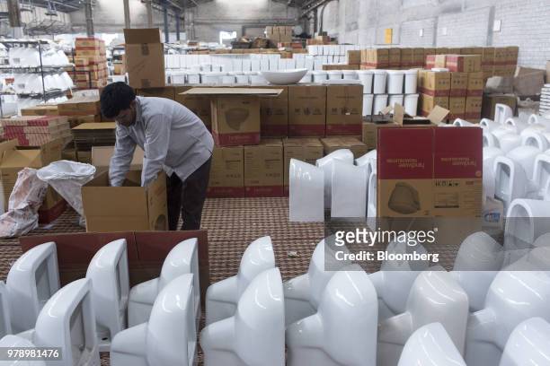 An employee packs a Dome toilet bowl from the Hindware Italian Collection at the HSIL Ltd. Factory in Bahadurgarh, Haryana, India, on Monday, June...