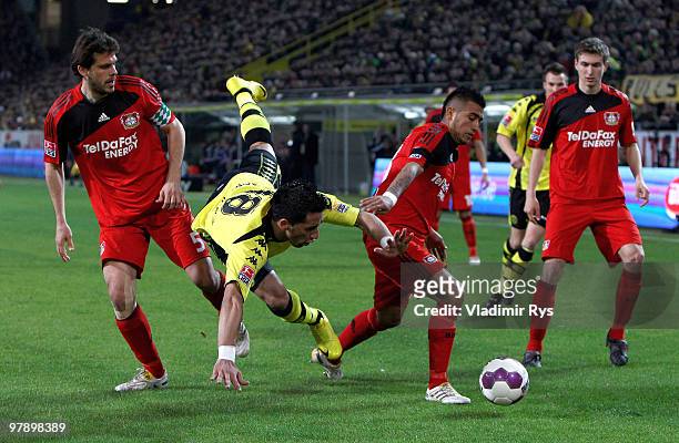 Lucas Barrios of Dortmund falls after a battle with Manuel Friedrich and Arturo Vidal of Leverkusen during the Bundesliga match between Borussia...
