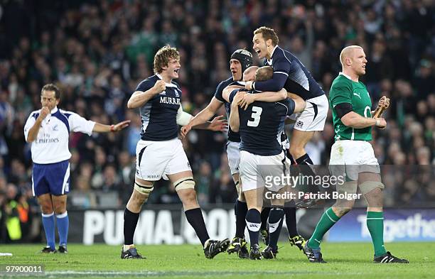 Richie Gray, Kelly Brown, Euan Murray and Dan Parkes of Scotland celebrate at the final whistle as a dejected Paul O'Connell leaves the field at the...
