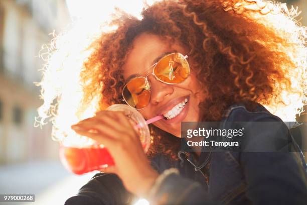 beautiful young woman with afro, summer time. - woman drinking juice stock pictures, royalty-free photos & images