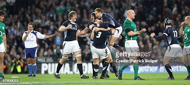 Richie Gray, Kelly Brown, Euan Murray and Dan Parkes of Scotland celebrate at the final whistle as a dejected Paul O'Connell leaves the field at the...