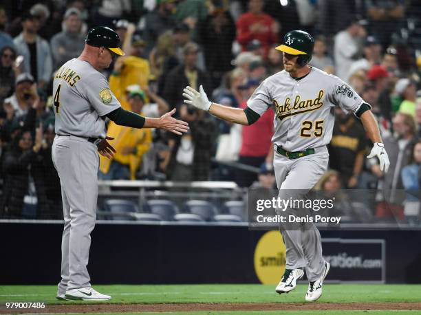 Stephen Piscotty of the Oakland Athletics is congratulated by Matt Williams after hitting a solo home run during the ninth inning of a baseball game...