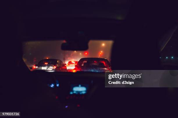 night time busy street view with illuminated car lights seen through car windshield at traffic jam - stau stock-fotos und bilder