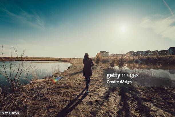 rear view of woman walking relaxing by river on walkway - city footpath stock pictures, royalty-free photos & images