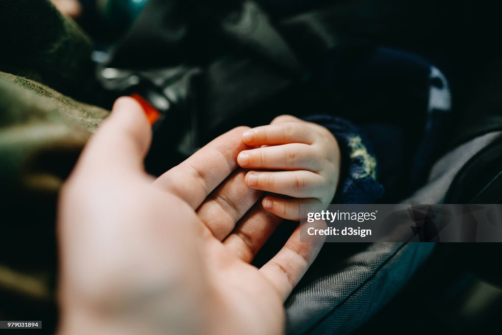 Close up of father holding baby's hand gently