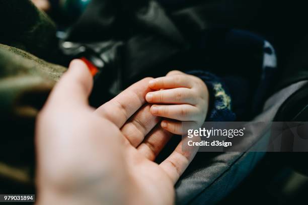close up of father holding baby's hand gently - baby car seat stock pictures, royalty-free photos & images