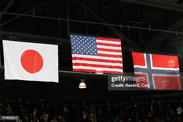 The flag of the United States , the flag of Japan and the flag of Norway hang above the arena in honor of the medal-winning countries during the Ice...