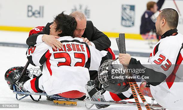 Ray Maluta, head coach of the United States, hugs Daisuke Uehara of Japan after the Ice Sledge Hockey Gold Medal Game between the United States and...