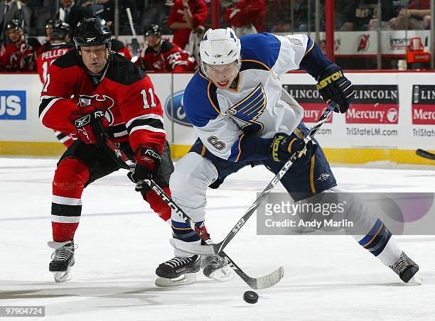 Erik Johnson of the St. Louis Blues and Dean McAmmond of the New Jersey Devils battle for a loose puck during the game at the Prudential Center on...