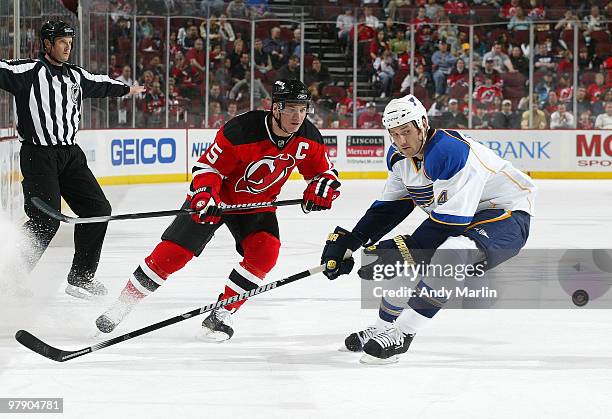 Eric Brewer of the St. Louis Blues and Jamie Langenbrunner of the New Jersey Devils eye a loose puck during the game at the Prudential Center on...