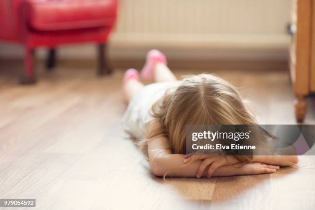 sulking girl lying on floor with head in hands - malumore foto e immagini stock