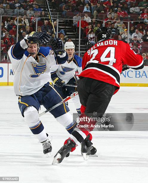 Cam Janssen of the St. Louis Blues is checked by Bryce Salvador of the New Jersey Devils during the game at the Prudential Center on March 20, 2010...