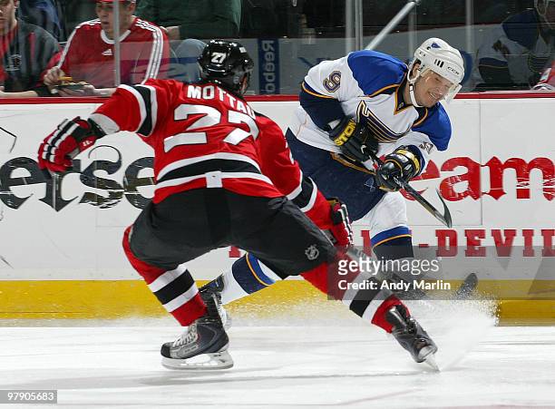 Paul Kariya of the St. Louis Blues fires a shot while being defended by Mike Mottau of the New Jersey Devils during the game at the Prudential Center...