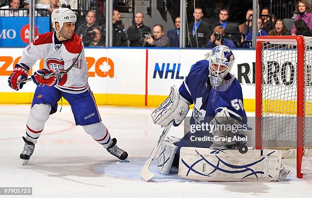 Jonas Gustavsson of the Toronto Maple Leafs makes a glove save with Scott Gomez of the Montreal Canadiens on the doorstep during game action March...