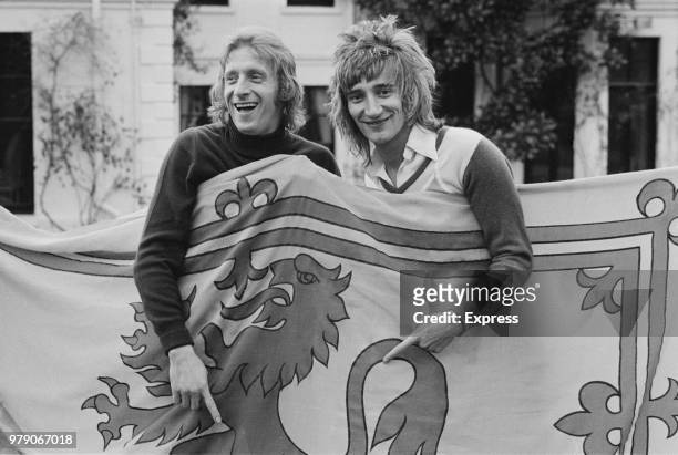 Scottish soccer player Denis Law of Manchester City FC with British singer-songwriter Rod Stewart, both are holding a Royal Banner of Scotland, UK,...
