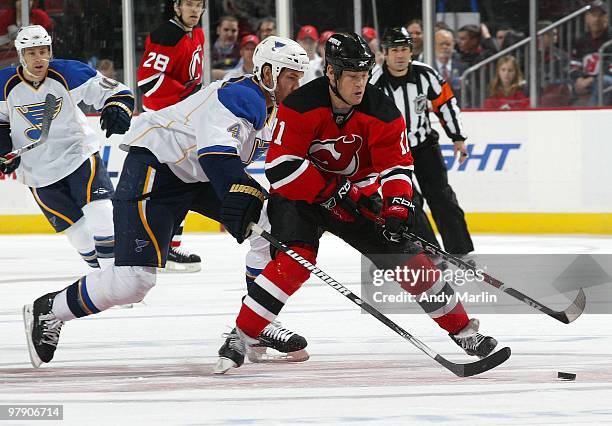 Eric Brewer of the St. Louis Blues and Dean McAmmond of the New Jersey Devils pursue a loose puck during the game at the Prudential Center on March...