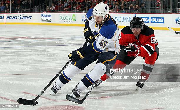 Jay McClement of the St. Louis Blues skates against Andy Greene of the New Jersey Devils at the Prudential Center on March 20, 2010 in Newark, New...