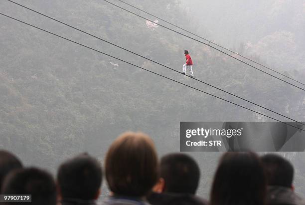 Onlookers gather as Swiss tightrope walker Freddy Nock attempts to scale the 690 meter-long cable car line on Zhangjiajie mountain, using only a...