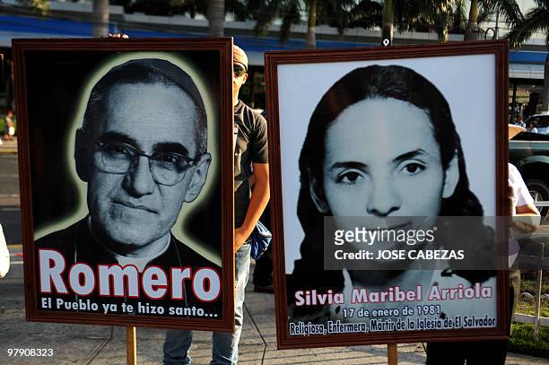 Catholic faithfuls hold pictures of Archbishop Oscar Arnulfo Romero and Sister Silvia Maribel Arriola during a procession to conmemorate the 30...