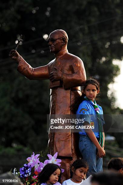 Girl scout stands next to the sculpture in the honor of Oscar Arnulfo Romero during a procession to conmemorate the 30 anniversary of the murder of...