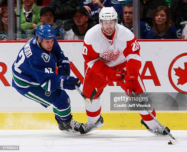 Drew Miller of the Detroit Red Wings skates with the puck while being defended by Kyle Wellwood of the Vancouver Canucks during their game at General...