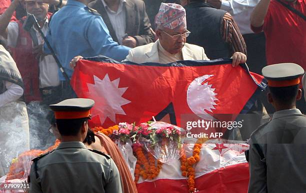 Nepal's Prime Minister Madhav Kumar Nepal lays the national flag over the body of former prime minister Girija Prasad Koirala in Kathmandu on March...