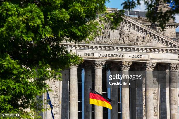 the famous inscription on the architrave on the west portal of the reichstag building in berlin: "dem deutschen volke" with german flag - architrave stock pictures, royalty-free photos & images