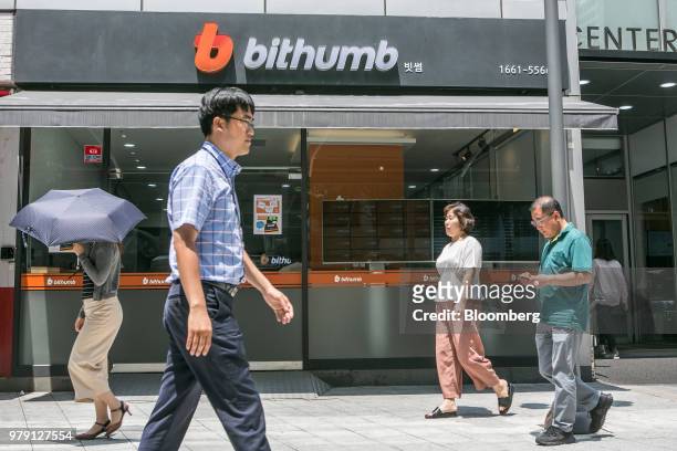 Pedestrians walk past a Bithumb exchange office in Seoul, South Korea, on Wednesday, June 20, 2018. Virtual currencies dropped after Bithumb, the...