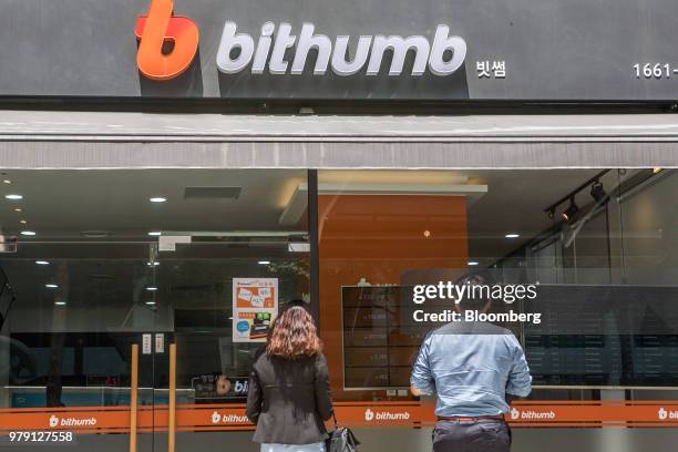 People look at a monitor displaying the prices of cryptocurrencies at a Bithumb exchange office in Seoul, South Korea, on Wednesday, June 20, 2018....