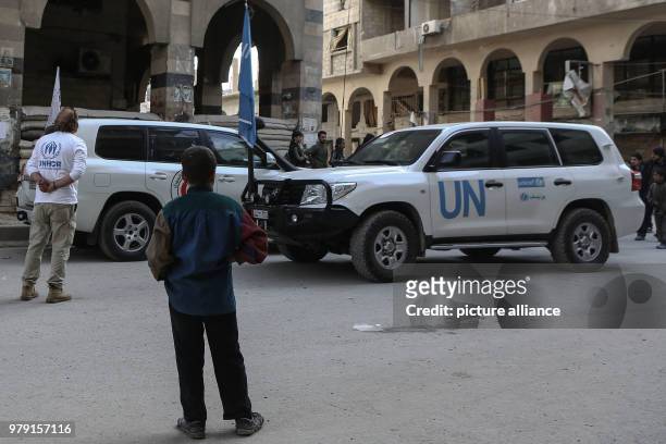 Dpatop - A Syrian boy watches an aid convoy of UN Agencies driving through the rebel-held city of Douma, Eastern Ghouta province, Syria, 05 March...