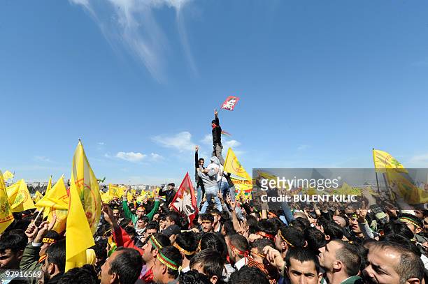 Turkish Kurds hold up Kurdish flags and chant slogan around the flames during a rally to celebrate the Kurdish New Year, known as 'Nowruz', on March...