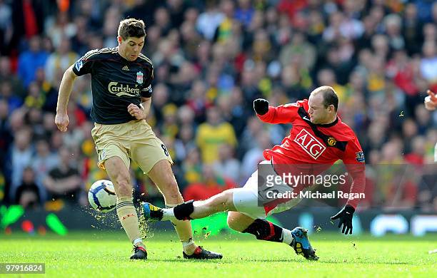 Steven Gerrard of Liverpool is tackled by Wayne Rooney of Manchester United during the Barclays Premier League match between Manchester United and...