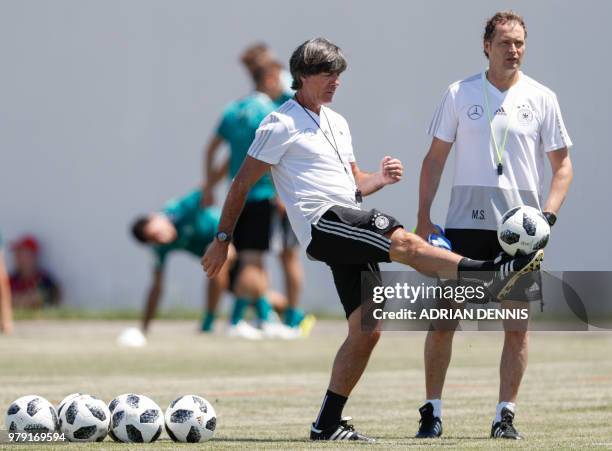 Germany's coach Joachim Loew kicks a ball next to his assistant Marcus Sorg during a training session at the Olympic Park Arena in Sochi on June 20...